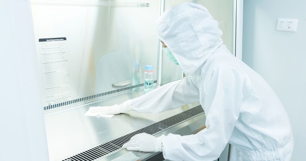 A person wearing protective gear as they clean lab equipment with acetone.