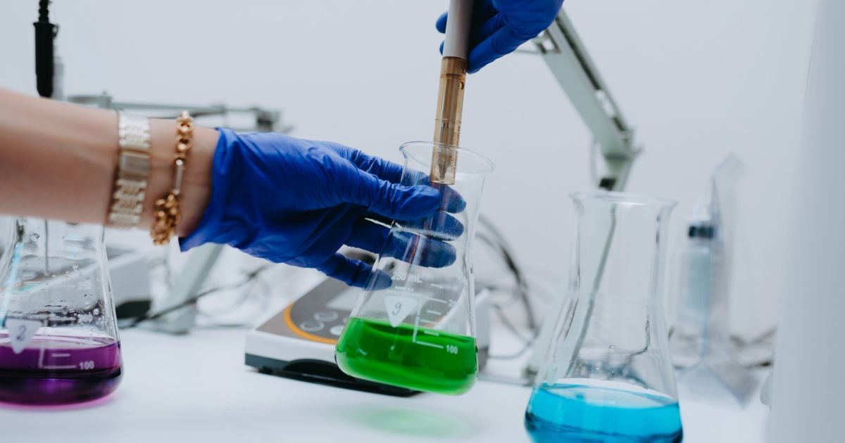 A person filling a beaker with liquid.