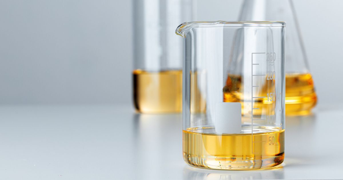 Three different shaped beakers filled with a yellow liquid.