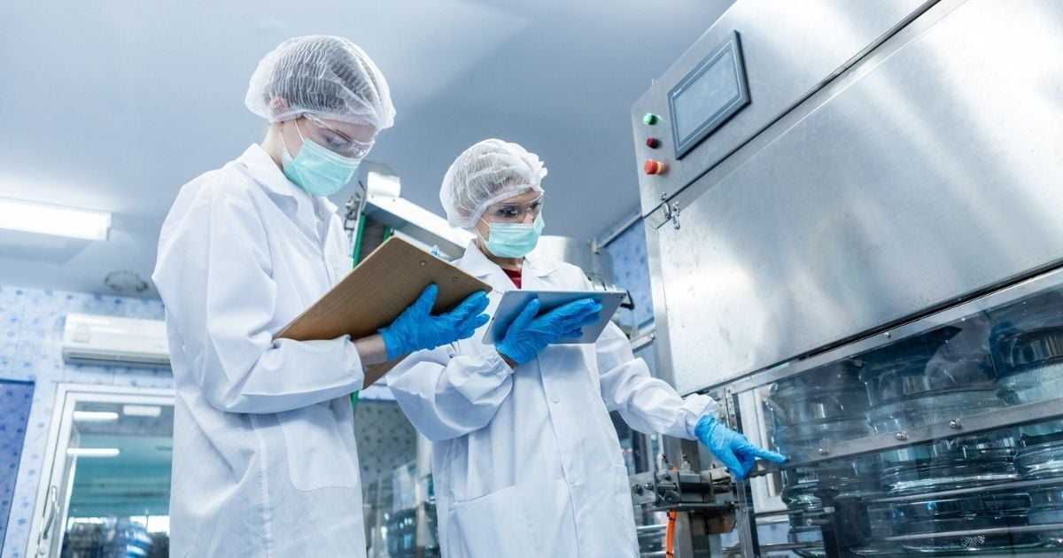 Two female scientists inspecting lab equipment for cleanliness.
