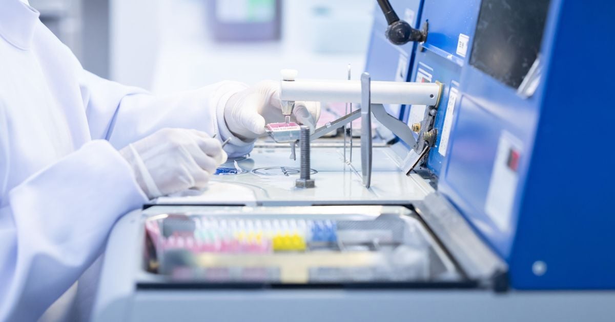 Laboratory technician conducting analysis with advanced equipment in a clean room environment.