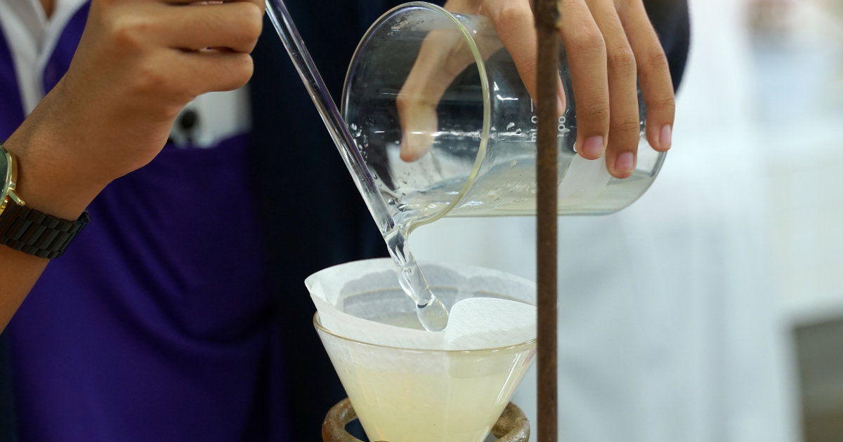 A lab tech using filter paper for a filtration system in a lab.