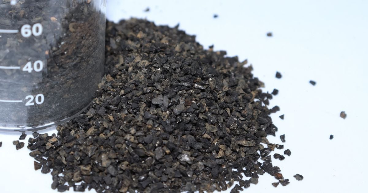 A carbon media material next to a beaker used for filtration and separation.