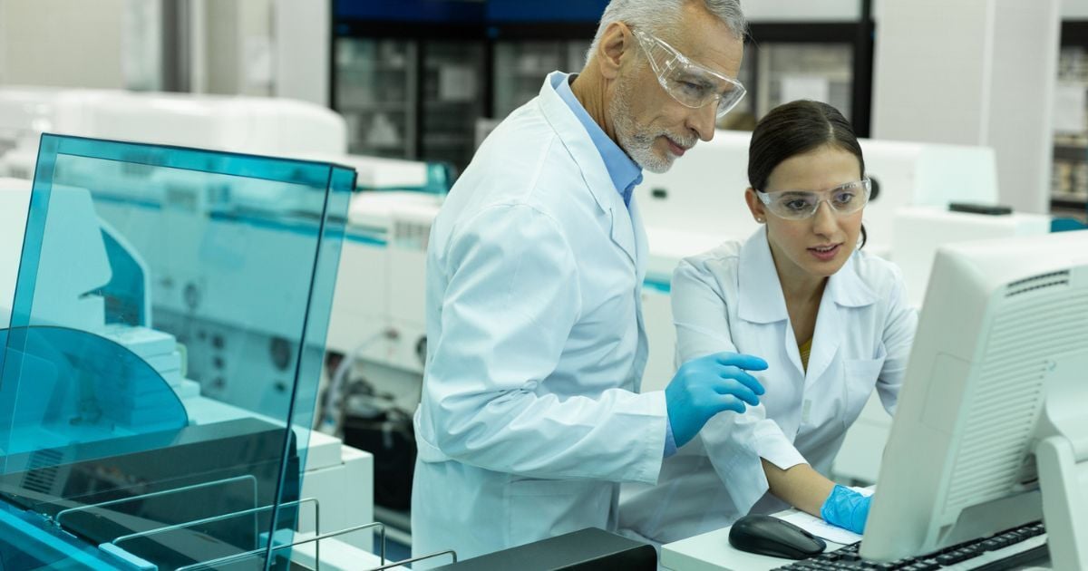 A female scientist showing a male lab tech a sensor drift issue on a lab computer.