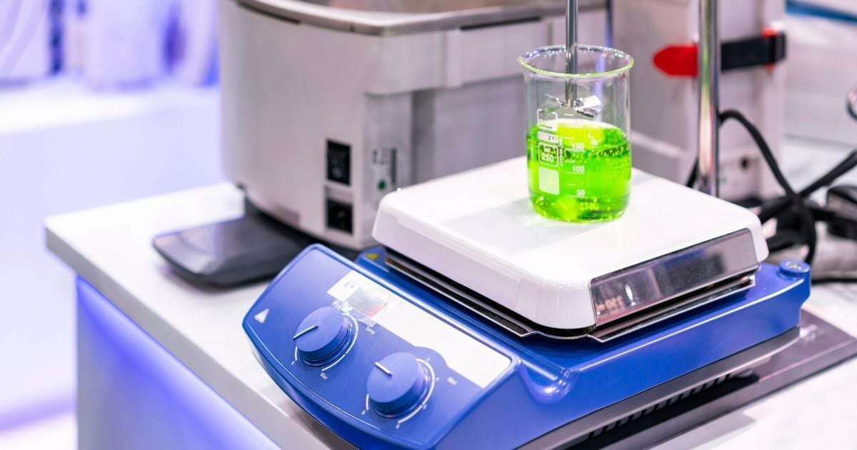 A mechanical stirrerr above a flask filled with a green liquid.