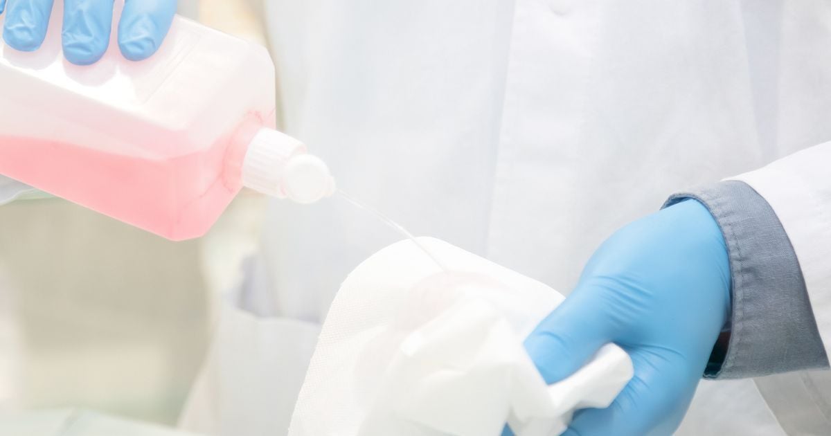 A person wearing gloves squirting cleaning solvent on a cloth.