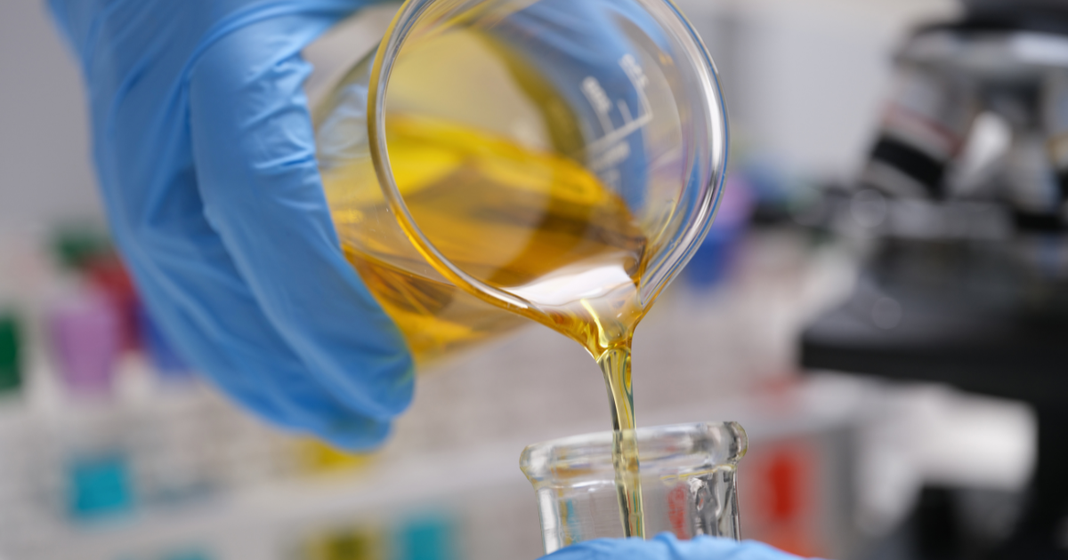 Liquid being poured from a flask into another glass flask after butane extraction.