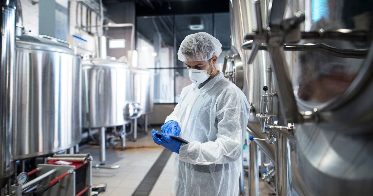 A lab tech inspecting solvent tanks and storage vessels.