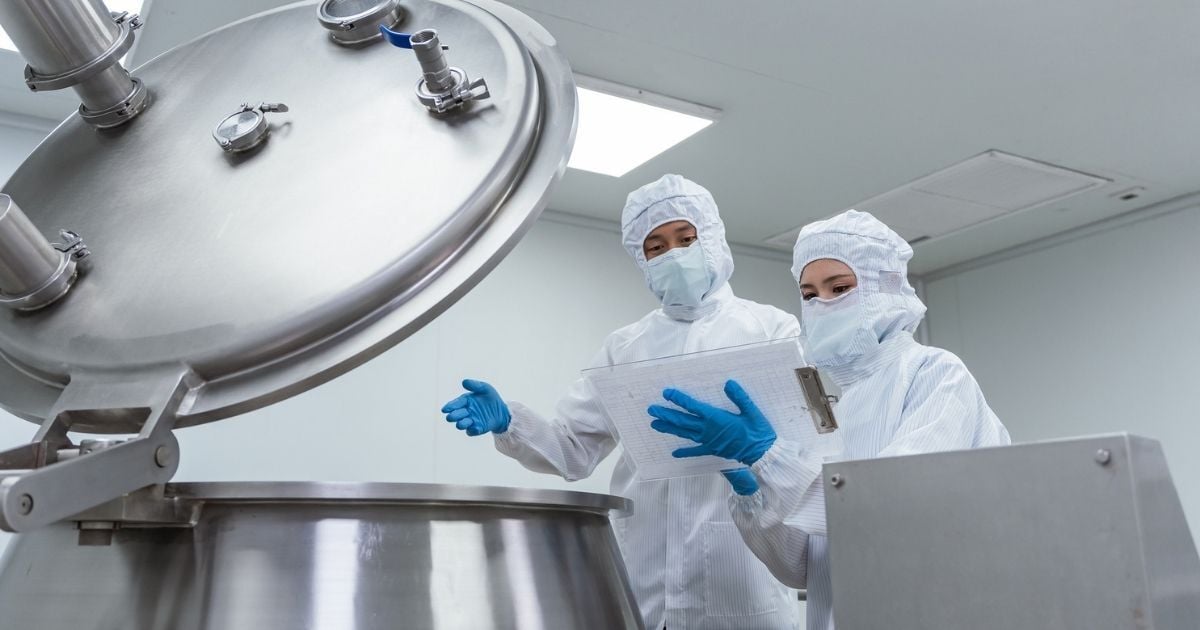Two lab techs inspecting a storage vessel for contamination.