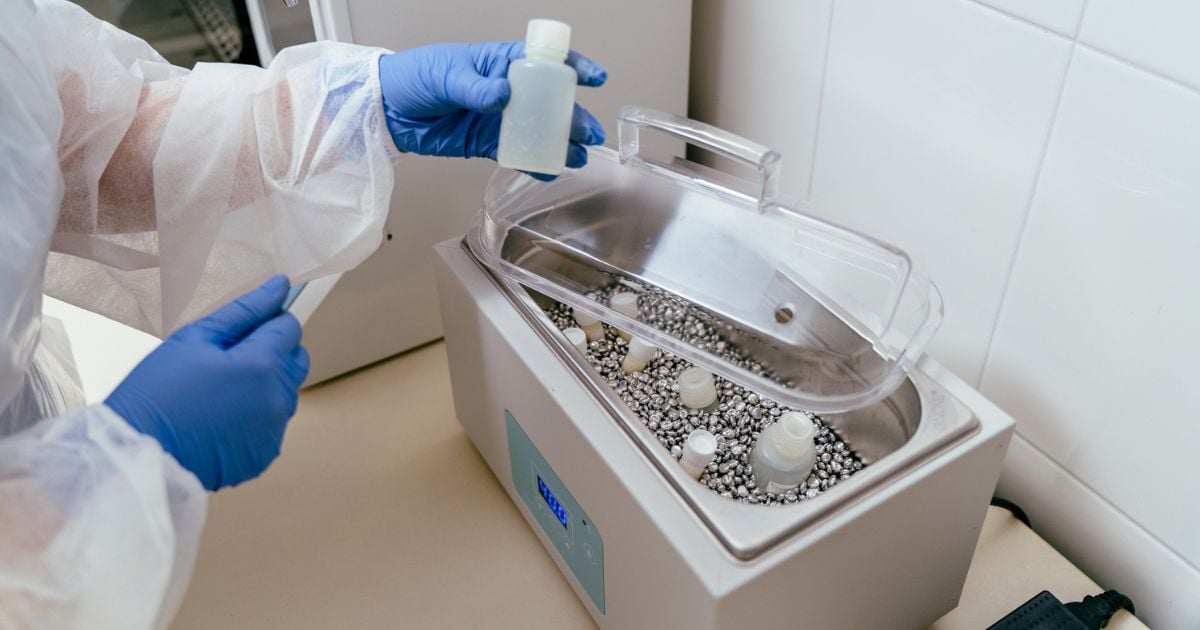Technician prepares bottles by placing it into a bead bath in clinical lab setting.