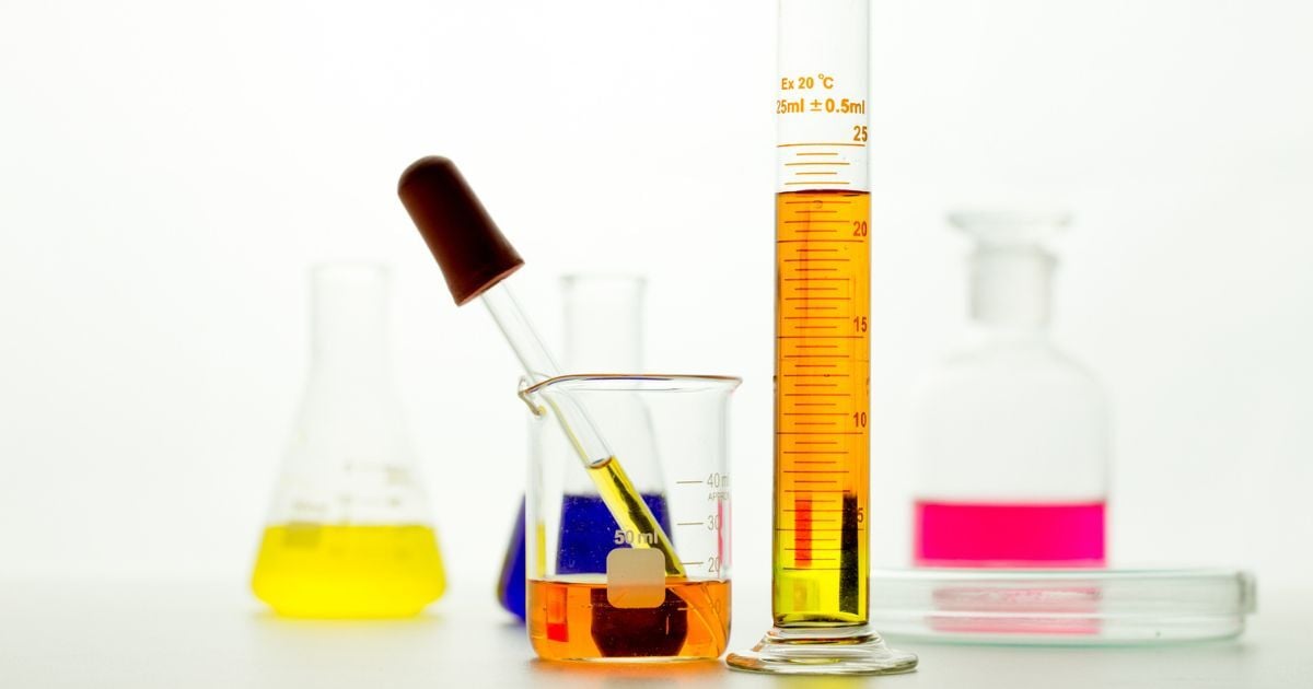 A graduated cylinder next to a beaker and dropper filled with yellow liquid.