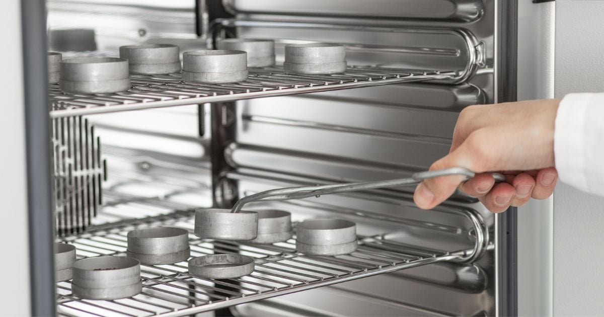 A lab tech removing samples from a forced air oven.